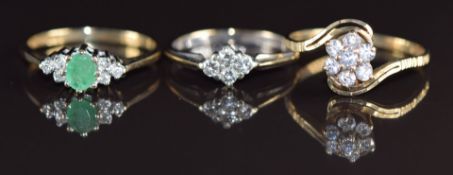 Three 9ct gold rings, one set with an oval cut emerald and diamonds, one four diamonds and the other