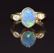 An 18ct gold ring set with an oval black opal cabochon and diamonds, 5.4g, size K