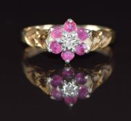 A 9ct gold ring set with a diamond surrounded by rubies, with pierced shoulders, 1.9g, size O