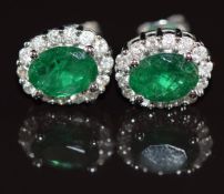 A pair of 14k white gold earrings each set with an oval cut emerald of approximately 0.75ct