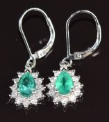 A pair of 18k white gold earrings each set with a pear cut emerald of approximately 0.8ct surrounded