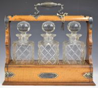 19th or early 20thC tantalus, with three cut glass decanters mounted in an oak and silver plate