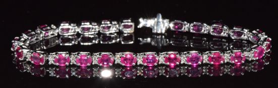 A 14k white gold tennis bracelet set with 26 oval cut rubies, each approximately 0.35ct, and
