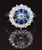 An 18k white gold ring set with diamonds and sapphires in a tiered cluster setting, the centre