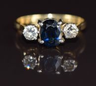 An 18ct gold ring set with an oval cut sapphire of approximately 1.2ct and two diamonds each