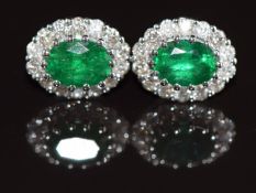 A pair of 18ct white gold earrings each set with an oval cut emerald of approximately 1.75ct