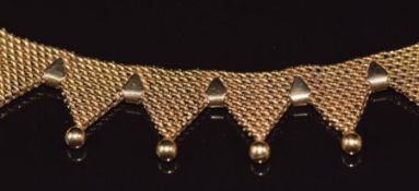 An 18ct gold collarette necklace, the 35 triangular sections each with spherical decoration,