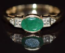 A 14k gold ring set with an oval cut emerald of approximately 0.65ct and diamonds, 2.9g, size M