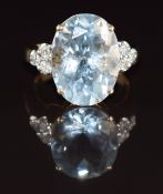 An 18ct gold ring set with an oval mixed cut aquamarine of approximately 9.4ct and three diamonds to