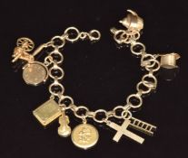 A 9ct gold charm bracelet with nine 9ct gold charms including 'Happy Days' spinning charm, cross,