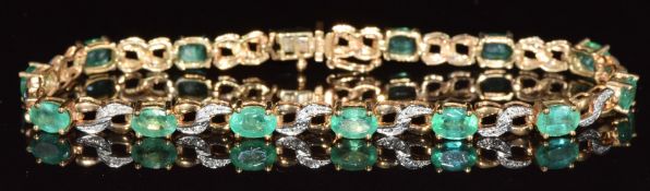 A 9ct gold ring set with 14 oval cut emeralds, each approximately 0.4ct and diamonds, 8.2g, 18cm