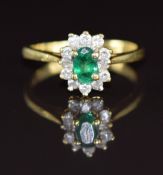 An 18ct gold ring set with an oval cut emerald of approximately 0.5ct surrounded by diamonds, 4g,