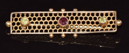 A c1910 9ct gold brooch set with a garnet and two peridot, 2.2g, 4.3cm
