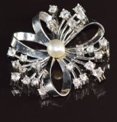 A platinum pendant / brooch set with a natural pearl and diamonds in a stylised floral design, the