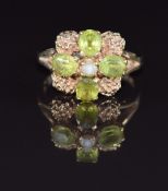 A 9ct gold ring set with a pearl surrounded by four oval cut peridot in a floral cluster, 4.8g, size
