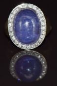 A 9ct gold ring set with a tanzanite cabochon surrounded by diamonds, 6.9g, size M
