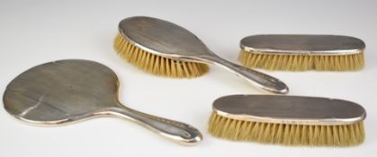 George V hallmarked silver four piece dressing table set comprising hand mirror and three brushes,