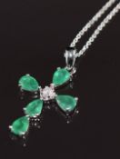 A 9k white gold pendant in the form of a cross set with emeralds totalling 2.1ct and a diamond of