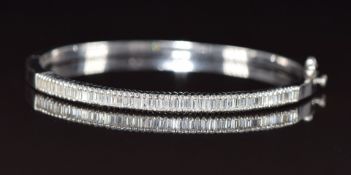 A 18k white gold bangle set with baguette cut diamonds, the total diamond weight approximately 1.