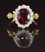 An 18ct gold ring set with an oval cut garnet of approximately 2.8ct surrounded by diamonds, 4.8g,