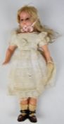 A wax over composition doll of a young girl with stuffed cloth body, blue glass eyes, blonde hair,