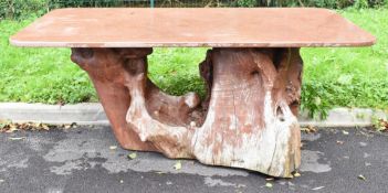 Pink marble topped garden table raised on a gnarled twin tree trunk natural wood base, possibly