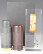 Three gun related paperweights comprising two rubber bullets and a clear encased firing shotgun