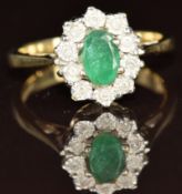 A 9ct gold ring set with an oval cut emerald surrounded by diamonds, 3g, size K