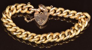 A 9ct gold curb link bracelet made up of alternating engraved and plain links, with heart padlock