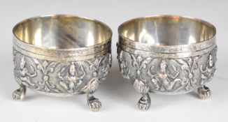 Pair of Indian or Burmese silver open salts embossed with deities and raised on three feet, diameter