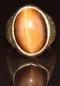 A 9ct gold ring set with a tiger's eye cabochon with textured shoulders, 7.4g, size L