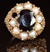 A 9ct gold ring set with an oval cut garnet surrounded by split pearls in a textured setting, 9.