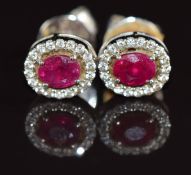 A pair of 18k white gold earrings each set with an oval cut ruby of approximately 0.3ct surrounded