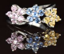 A 9k white gold ring set with blue sapphires, yellow sapphires and pink sapphires in three floral