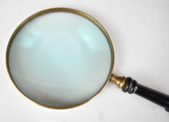 Novelty oversized magnifying glass with turned ebonised or similar handle and brass rim, length