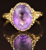 An 18ct gold ring set with an oval cut amethyst, with embellished shoulders, 3.9g, size N