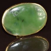 An 18ct gold ring set with a large oval jadeite plaque, maker RH, 19g, size O