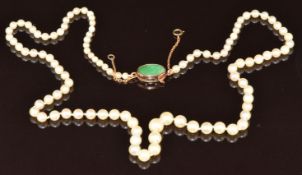 A single strand of cultured pearls, the 14k gold clasp set with jadeite, signed WK, 45cm