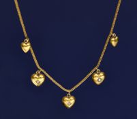 An Edwardian 15ct gold necklace with five drop heart pendants one set with an old cut diamond and