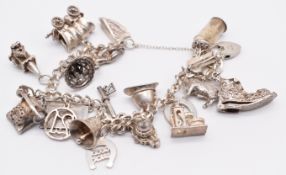A silver charm bracelet with nineteen silver charms including 'good luck' horseshoe, cherub, church,