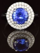 A platinum ring set with a round cut tanzanite of approximately 4ct surrounded by a border of two