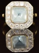 A c1930 18ct gold ring set with an emerald cut aquamarine of approximately 2ct surrounded by sixteen