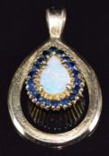 A 9ct and 18ct gold pendant set with a pear cut opal surrounded by sapphires, 7.3g, 3.5 x 2.2cm