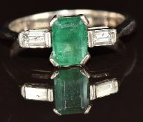 An 18ct white gold ring set with an emerald cut emerald and two baguette cut diamonds, 4.2g, size M