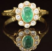 An 18ct gold ring set with an oval cut emerald of approximately 0.75ct surrounded by diamonds, 4.5g,