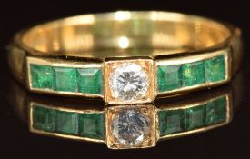 An 18ct gold ring set with a round cut diamond of approximately 0.18ct and calibre cut emeralds, 4.