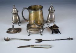 Hallmarked silver items comprising christening mug, three piece cruet set, pickle fork surmounted by