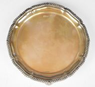 George V hallmarked silver card tray or small salver with gadrooned edge, raised on three feet,