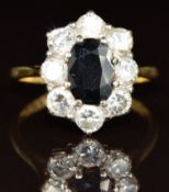 An 18ct gold ring set with an oval cut sapphire of approximately 1ct surrounded by nine diamonds