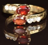 A 9ct gold ring set with two oval cut garnets and cubic zirconia, 3.9g, size O